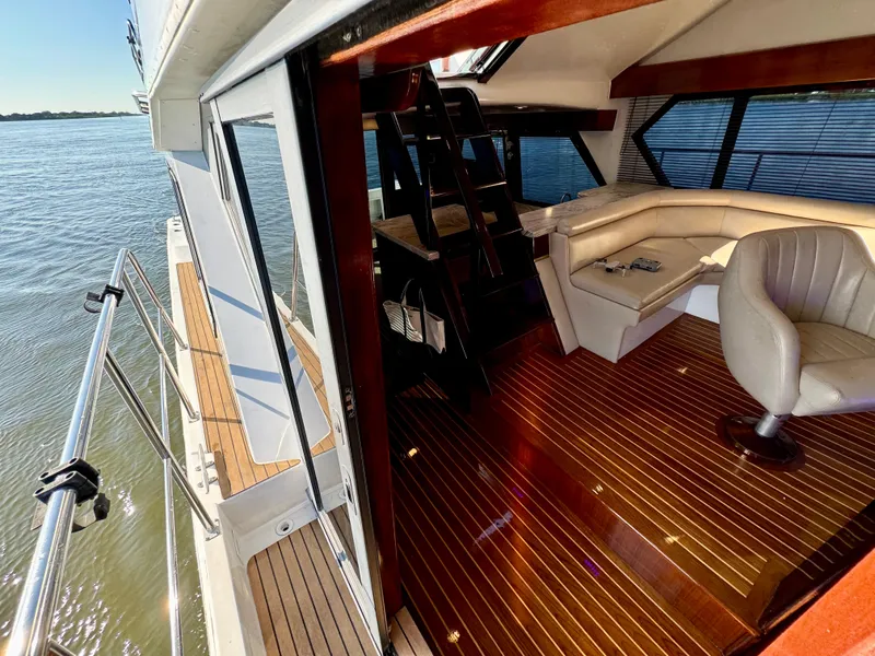 Slide: The Image of 1998 Navigator Pilothouse yacht interior with wooden flooring and leather seating by the water. - 41
