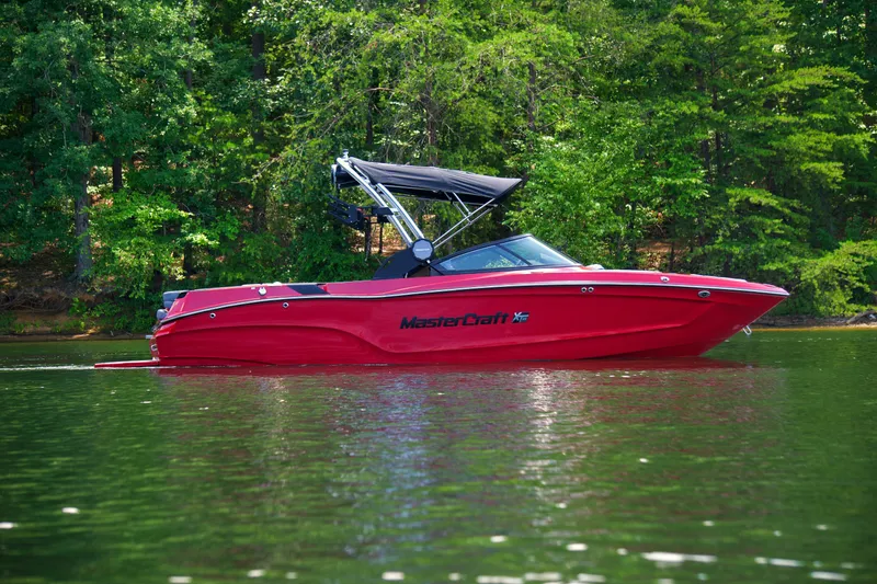 The Image of 2024 MasterCraft XT23 boat in vibrant red on a serene lake. - 0