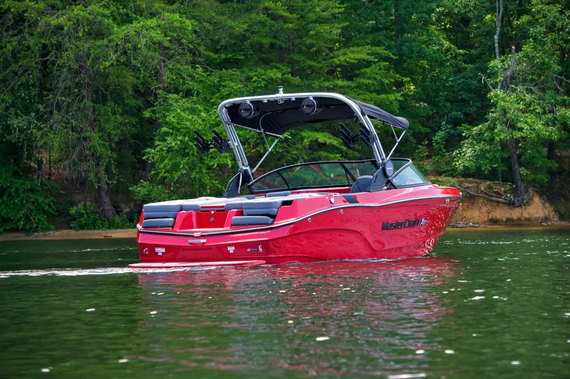 Slide: The Image of 2024 MasterCraft XT23 boat on a serene lake with lush green trees. - 4