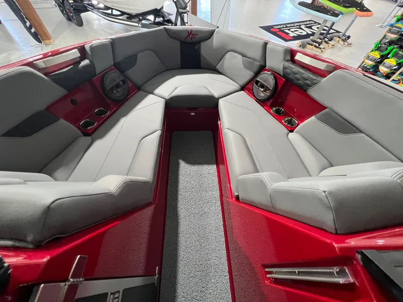 Slide: The Image of 2024 MasterCraft XT23 boat interior with red and gray seating, cup holders, and speakers. - 9
