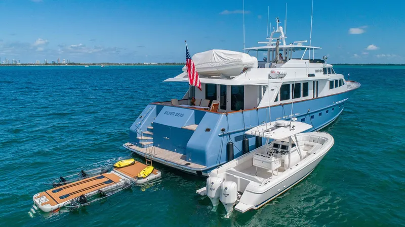 Slide: The Image of Luxury 1998 Burger Raised Pilothouse yacht with tender and paddleboards on blue ocean. - 10