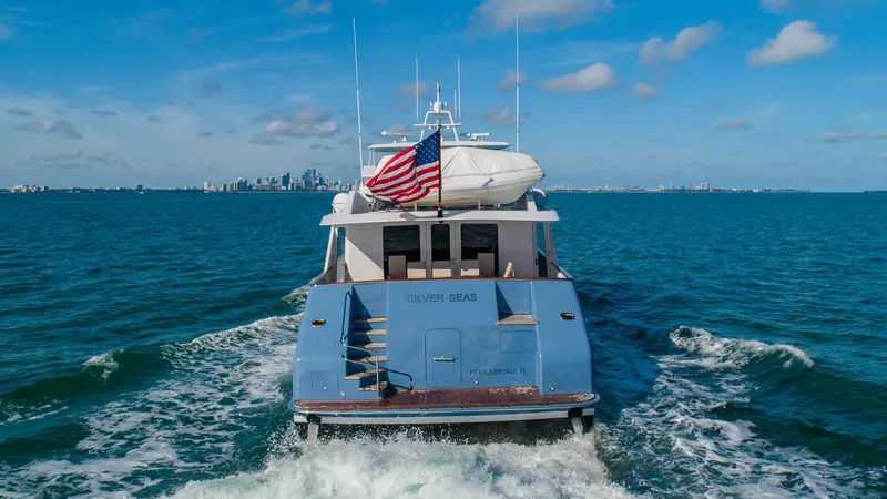 Slide: The Image of Luxury 1998 Burger Raised Pilothouse yacht cruising with American flag, city skyline in background. - 2
