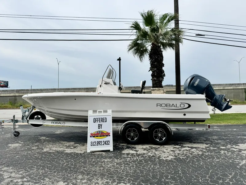 The Image of 2024 Robalo 226 Cayman boat on trailer, displayed outdoors with palm tree background. - 16