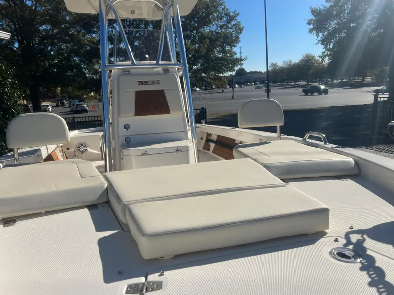 Slide: The Image of 2024 Pathfinder 2400 TRS boat with cushioned seating and sleek design in a sunny parking lot. - 7