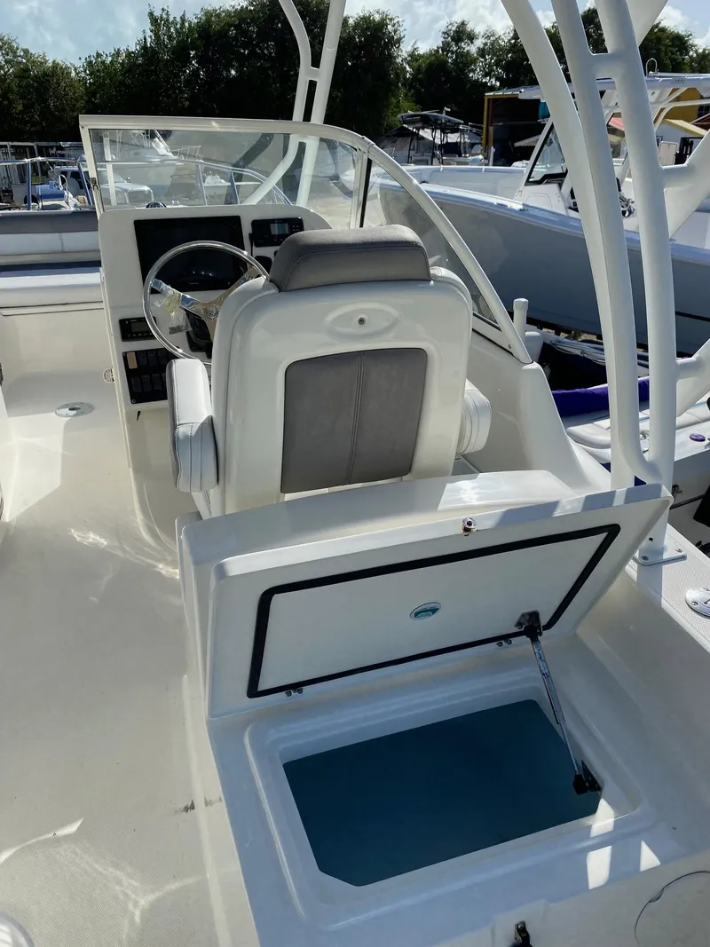 Slide: The Image of 2018 World Cat 255 DC boat interior with open storage compartment and steering wheel. - 12