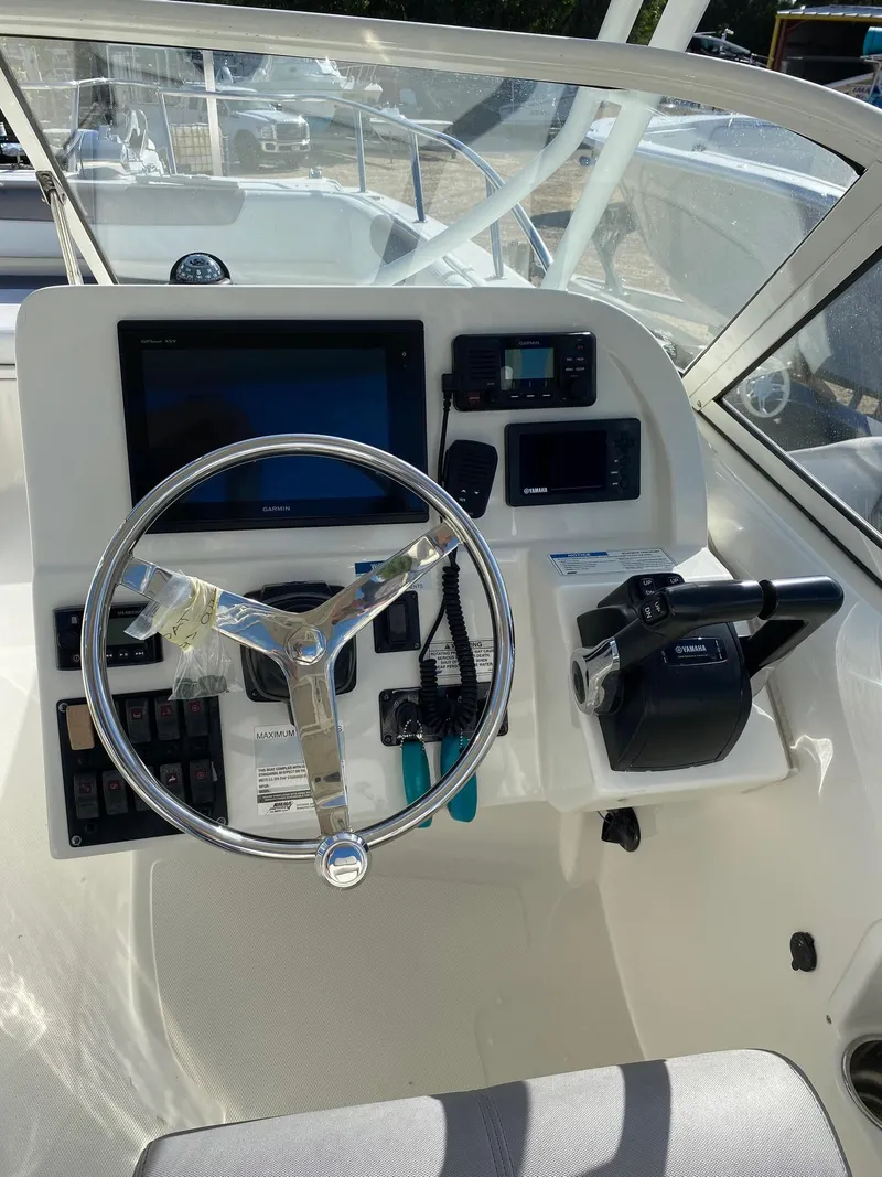 Slide: The Image of 2018 World Cat 255 DC boat dashboard with steering wheel and navigation controls. - 13