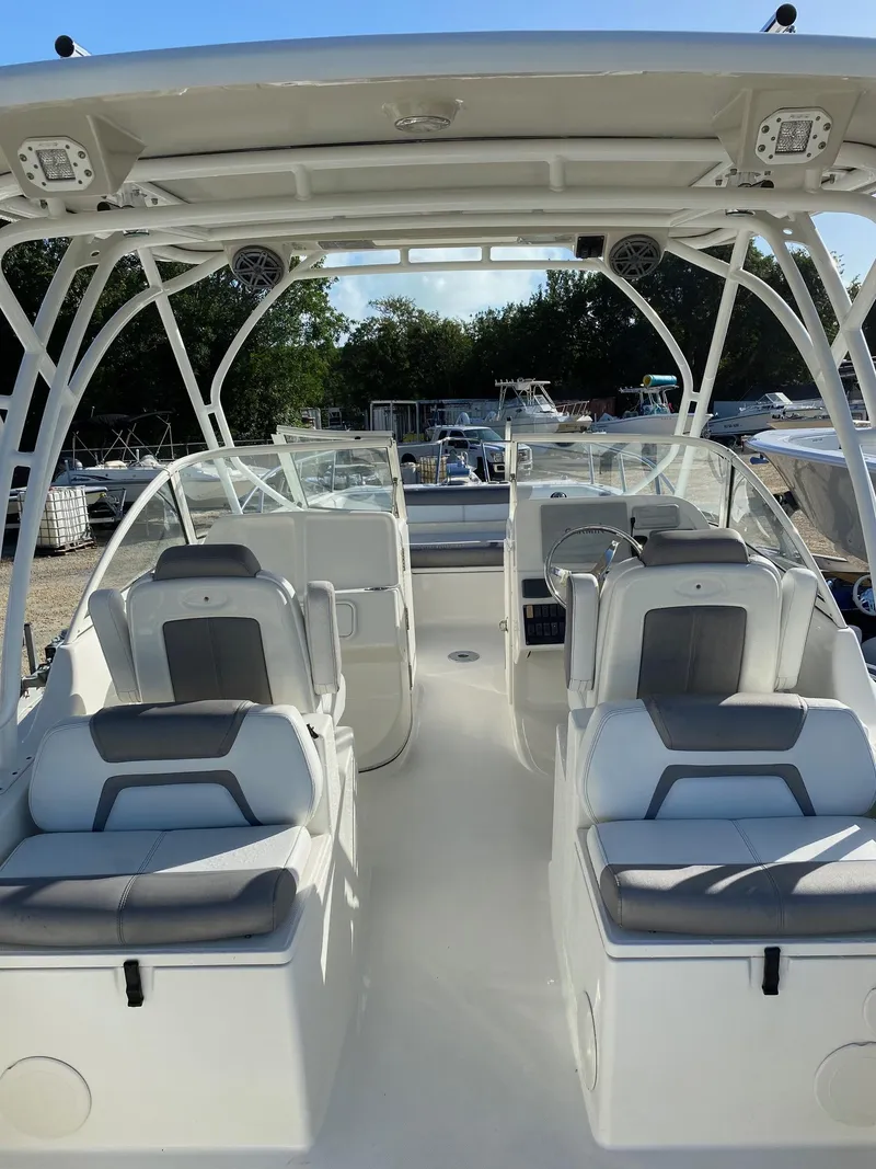 Slide: The Image of 2018 World Cat 255 DC boat interior with seating and helm, docked outdoors. - 7