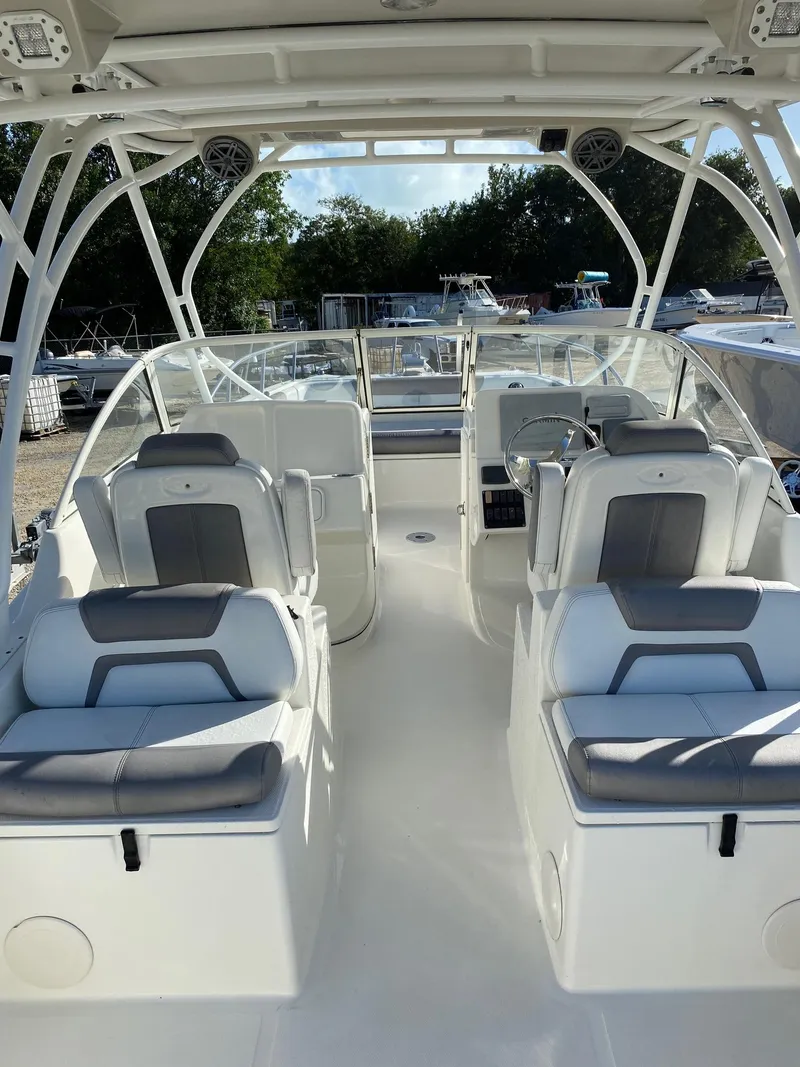 Slide: The Image of 2018 World Cat 255 DC boat interior with seating and helm, docked outdoors. - 8