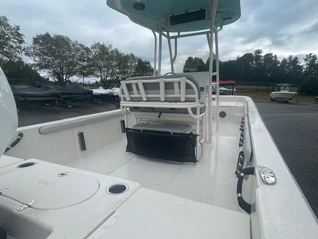 Slide: The Image of 2025 Carolina Skiff 23LS boat interior with seating and storage, parked outdoors. - 10