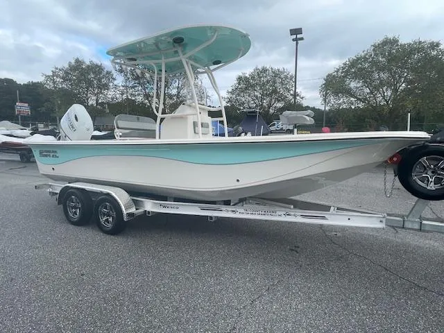 Slide: The Image of 2025 Carolina Skiff 23LS boat on trailer, featuring a sleek design and turquoise accents. - 2