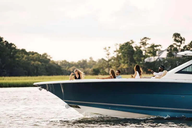 Slide: The Image of 2025 Scout 530 LXF boat cruising with passengers on a scenic waterway. - 2