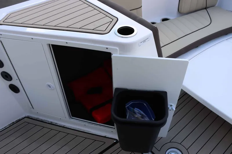 Slide: The Image of 2025 Yamaha Boats 222 FSH Sport E interior storage with life jacket and trash bin. - 9