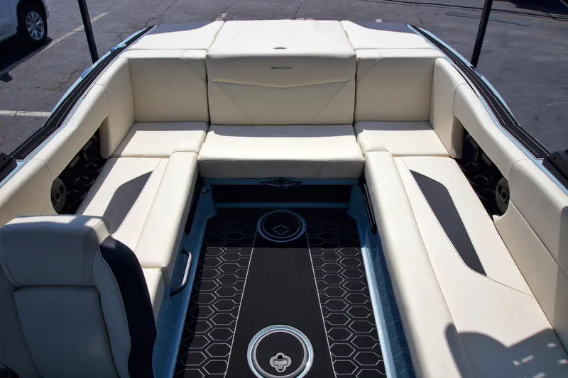 Slide: The Image of 2024 MasterCraft NXT23 boat interior with beige seating and black flooring. - 18