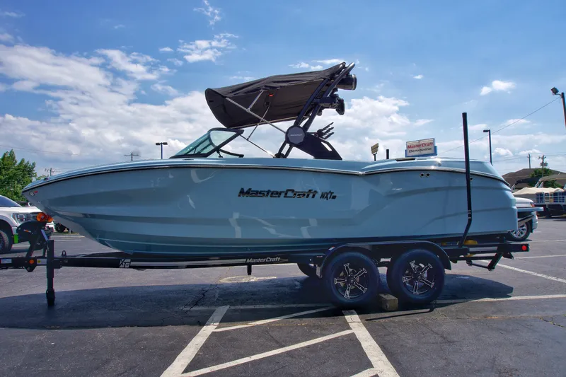 Slide: The Image of 2024 MasterCraft NXT23 boat on trailer in parking lot under blue sky. - 9
