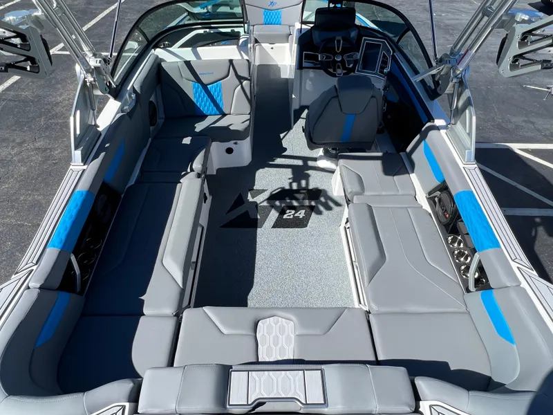 Slide: The Image of 2024 MasterCraft XT24 boat interior with gray and blue seating, modern dashboard, and spacious layout. - 11