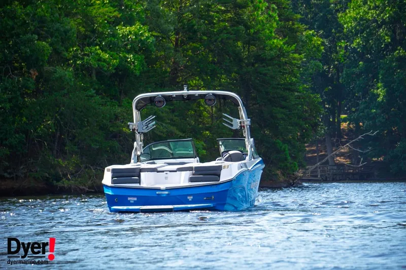 Slide: The Image of 2024 MasterCraft XT24 boat cruising on a scenic lake with lush green trees. - 3