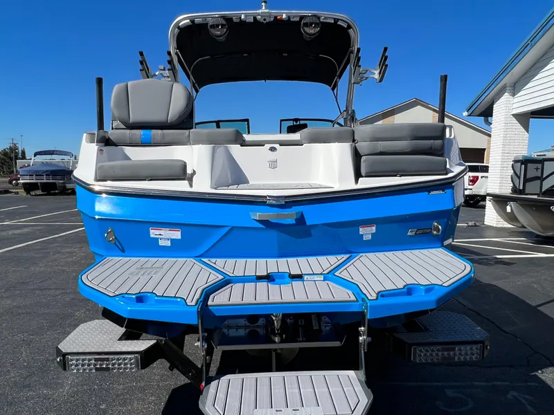 Slide: The Image of 2024 MasterCraft XT24 boat, blue and white, rear view with seating and swim platform. - 9