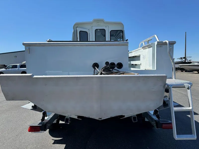 Slide: The Image of 2024 Hewescraft 270 Alaskan boat, rear view, parked on trailer under clear blue sky. - 10