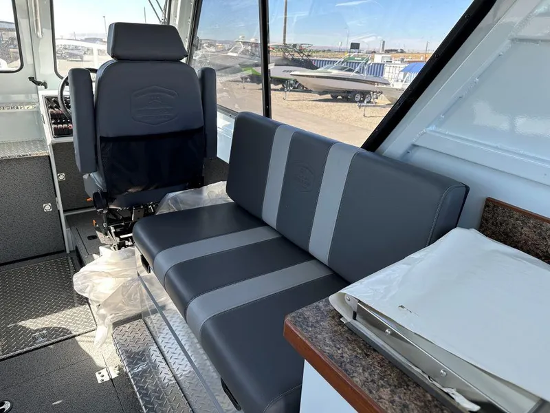 Slide: The Image of 2024 Hewescraft 270 Alaskan interior with gray seating and helm chair. - 5