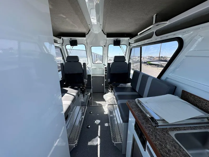 Slide: The Image of Interior of 2024 Hewescraft 270 Alaskan boat, featuring seating and a compact kitchenette. - 6