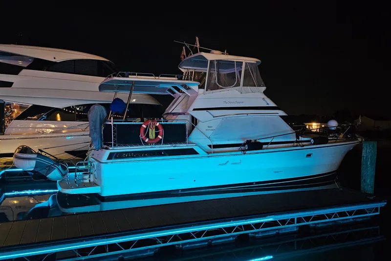 Slide: The Image of 1999 Riviera 40AC yacht docked at night with blue lighting. - 6