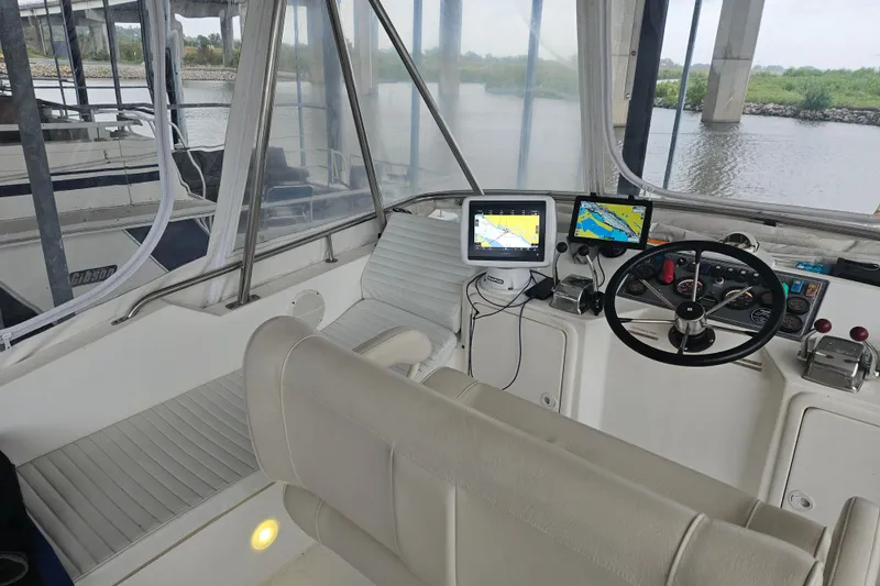 Slide: The Image of 1999 Riviera 40AC boat cockpit with navigation screens and steering wheel under a bridge. - 9