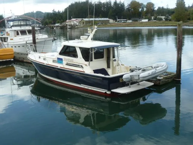 Slide: The Image of 2006 Sabre 38 Express boat docked in a serene marina setting. - 2
