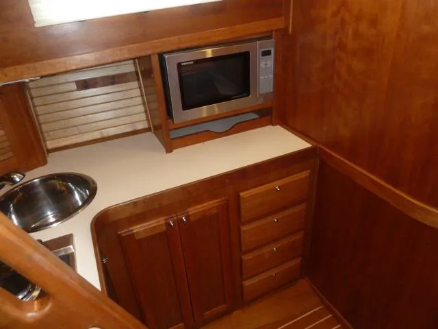 Slide: The Image of 2006 Sabre 38 Express yacht kitchen with microwave, sink, and wooden cabinetry. - 20