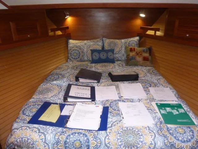 Slide: The Image of Cozy cabin bed in 2006 Sabre 38 Express with manuals and documents spread out. - 23