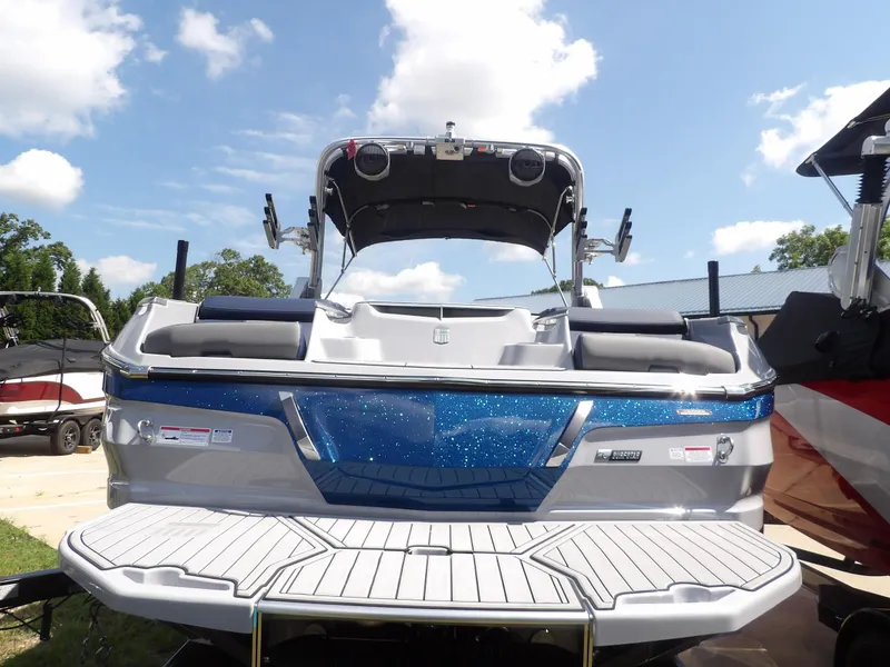 Slide: The Image of 2024 MasterCraft X24 boat with blue accents and spacious deck under a clear sky. - 11