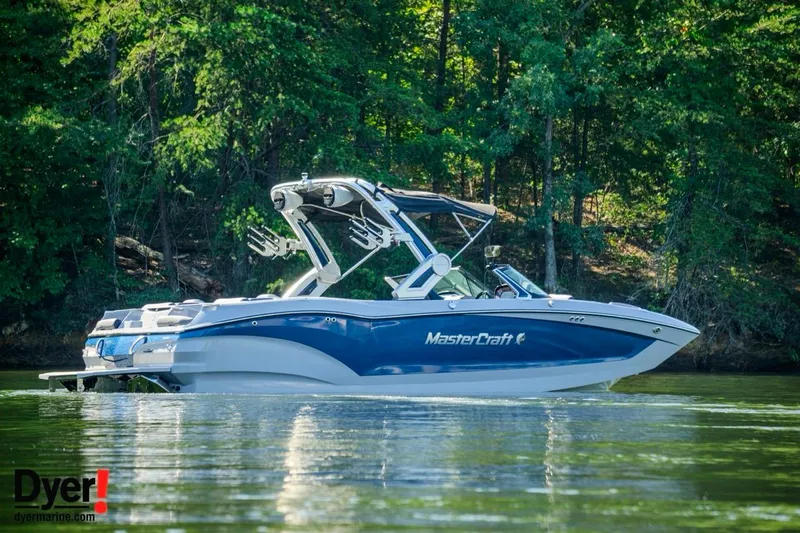 Slide: The Image of 2024 MasterCraft X24 boat on a serene lake with lush green forest backdrop. - 3