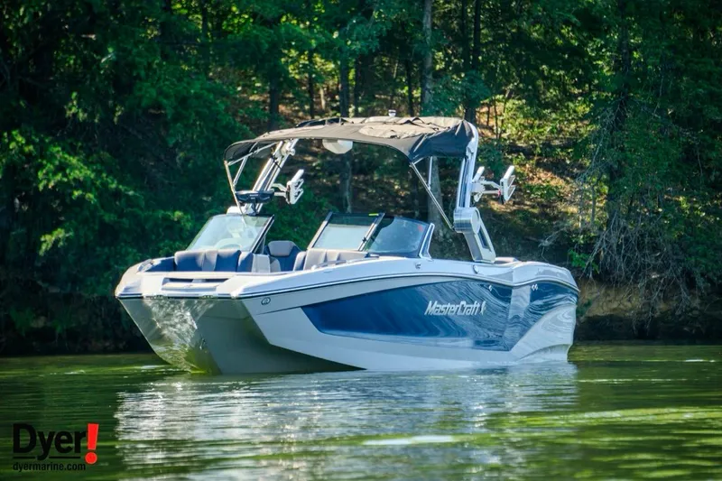 Slide: The Image of 2024 MasterCraft X24 boat on a serene lake with lush green forest backdrop. - 5