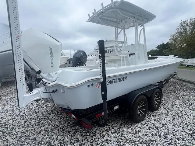 Slide: The Image of 2024 Contender 26 Bay boat on trailer with Mercury engine, parked on gravel. - 1