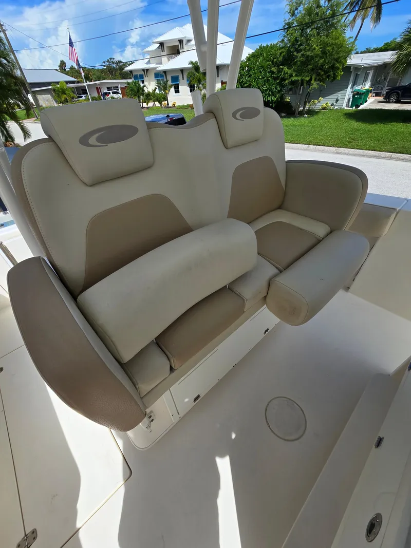 Slide: The Image of 2015 Cobia 296 Center Console boat seat, beige and white upholstery, outdoor setting. - 16