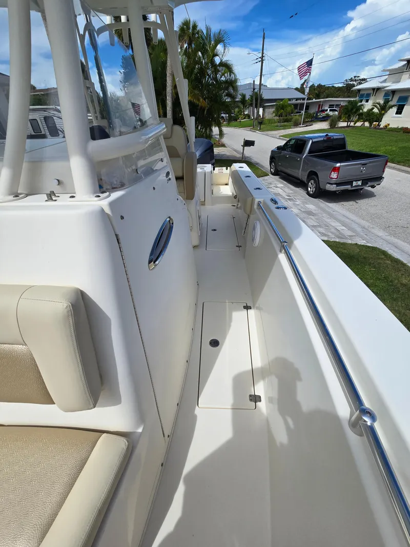 Slide: The Image of 2015 Cobia 296 Center Console boat interior with seating, parked truck in background. - 40