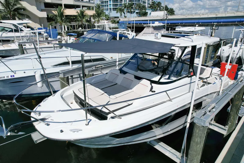 Slide: The Image of 2024 Jeanneau Leader 9.0WA S2 boat docked at marina, featuring sleek design and sunshade. - 0