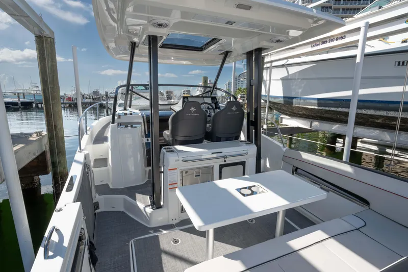 Slide: The Image of 2024 Jeanneau Leader 9.0WA S2 boat interior with seating and helm at marina. - 9
