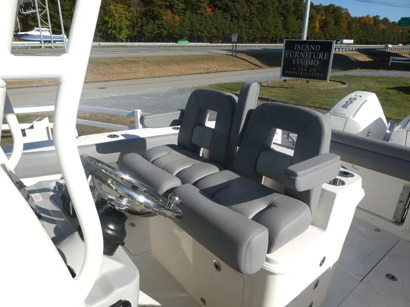 Slide: The Image of 2024 Boston Whaler 280 Outrage boat cockpit with dual gray seats and steering wheel. - 13