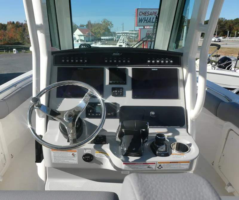 Slide: The Image of 2024 Boston Whaler 280 Outrage helm with steering wheel and control panel. - 7