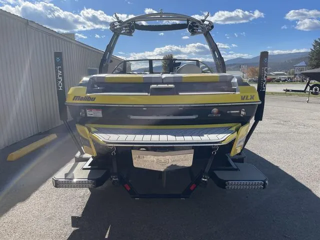 Slide: The Image of 2017 Malibu 21 VLX boat, yellow and black, parked outdoors under a blue sky. - 3