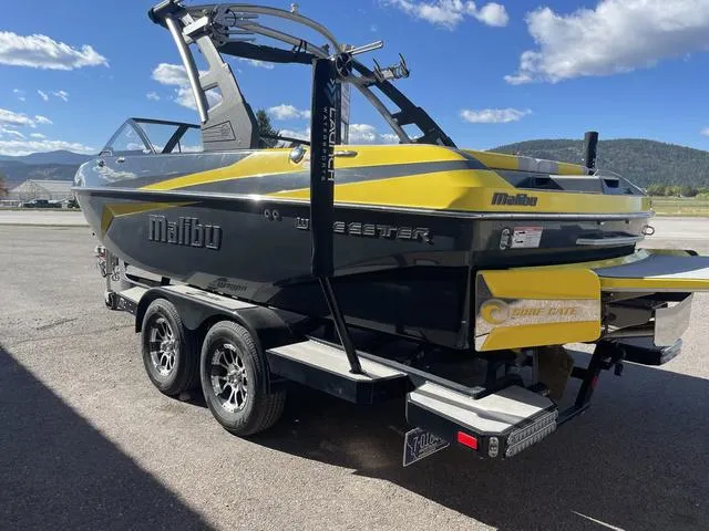 Slide: The Image of 2017 Malibu 21 VLX boat on trailer, yellow and black design, parked outdoors. - 4