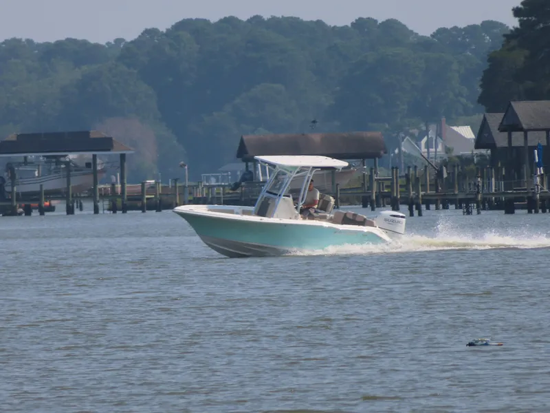 Slide: The Image of 2024 Key West 203 FS boat cruising on a calm river near docks and trees. - 27