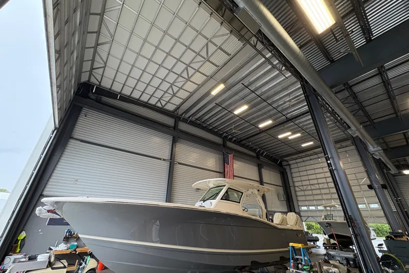 The Image of 2026 Scout 330 LXF boat in a warehouse, elevated on stands, with sleek design. - 0