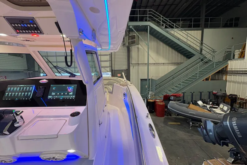 Slide: The Image of 2026 Scout 330 LXF boat interior with advanced controls and Yamaha engine in a warehouse. - 23