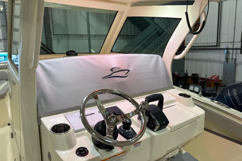 Slide: The Image of 2026 Scout 330 LXF boat helm with steering wheel and controls in a showroom. - 24