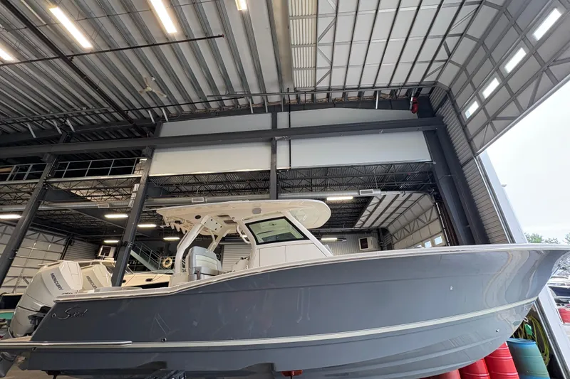 Slide: The Image of 2026 Scout 330 LXF boat in a warehouse, featuring sleek design and illuminated canopy. - 3