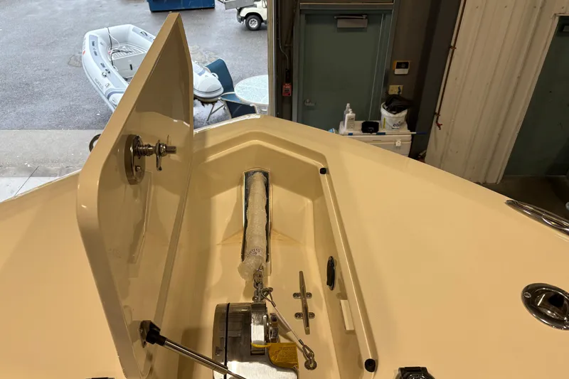 Slide: The Image of 2026 Scout 330 LXF boat anchor compartment with open hatch in a garage setting. - 41