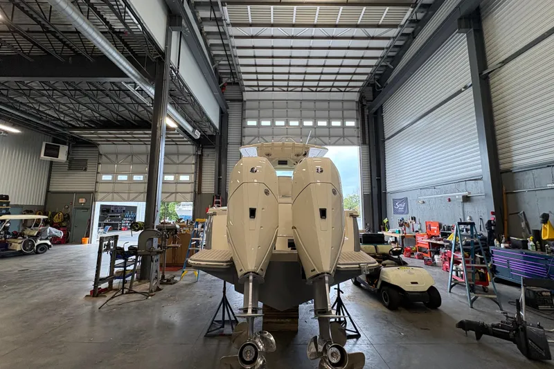 Slide: The Image of 2026 Scout 330 LXF boat in a warehouse, elevated on stands. - 5