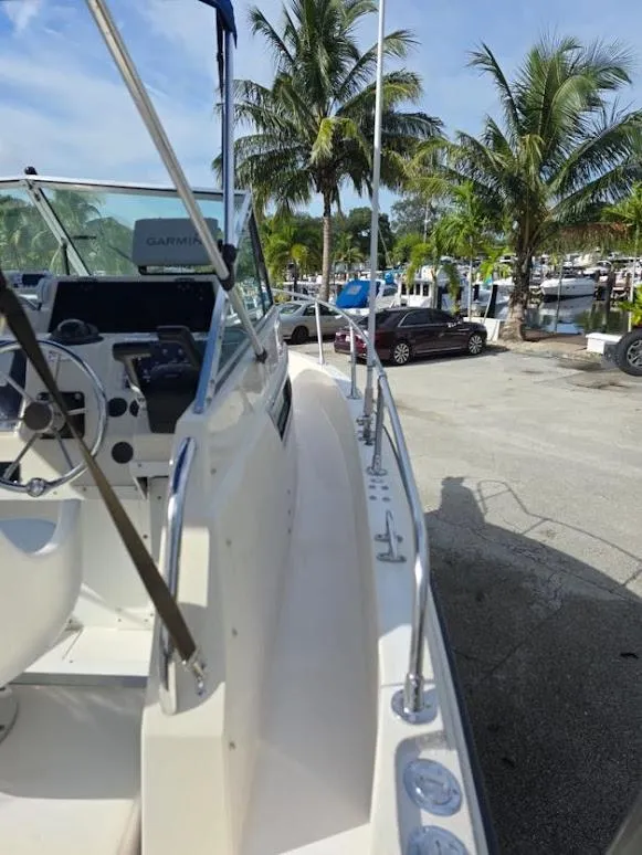 Slide: The Image of 1988 Grady-White 232 Gulfstream boat docked near palm trees and parked cars. - 10