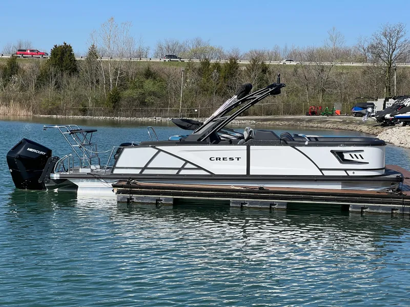 The Image of 2025 Crest Caribbean LX 230 SLRC pontoon boat docked on a serene lake. - 0